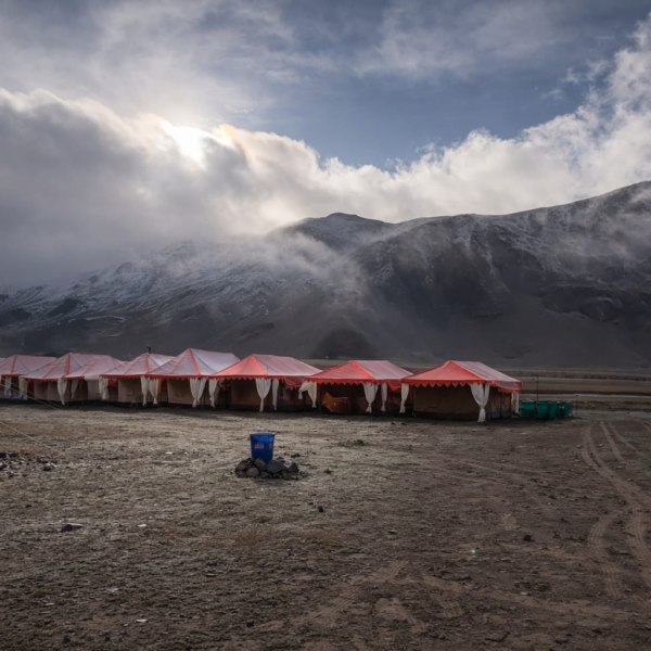 landscape view of a luxury tent colony in Sarchu plains on the Manali-Leh highway, surrounded by the rugged peaks of Lahaul.