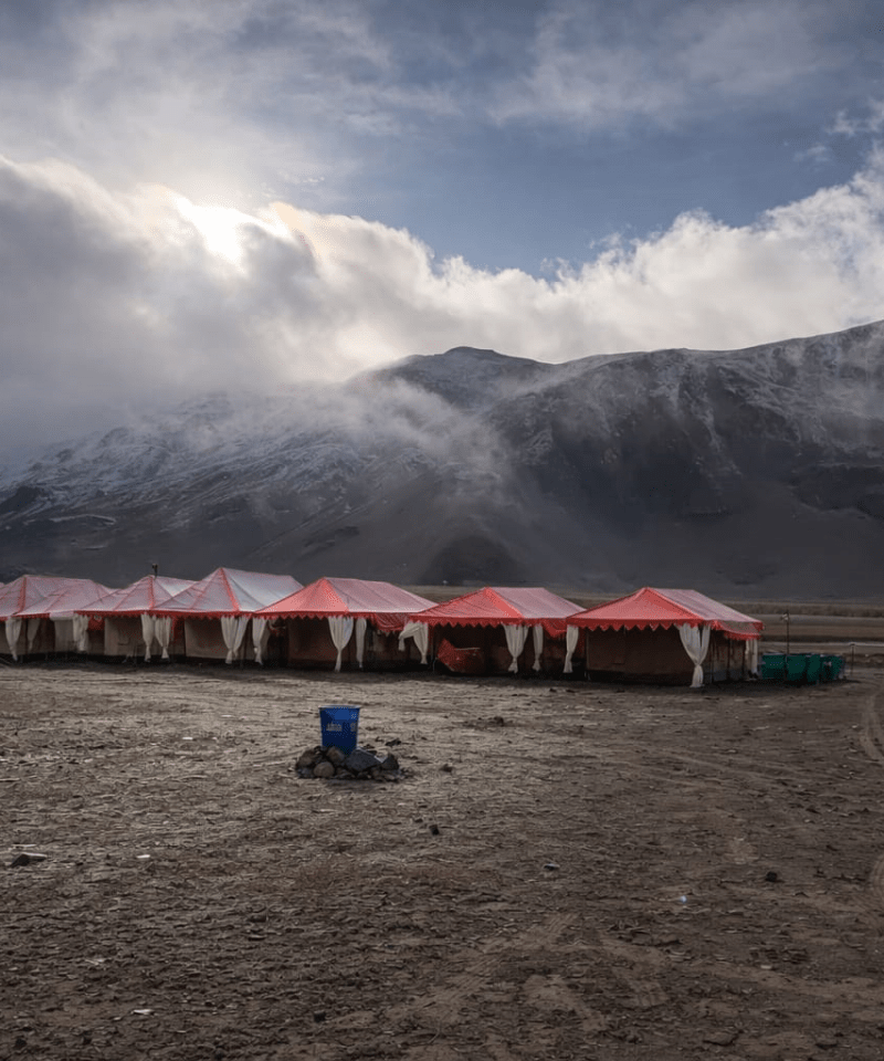 landscape view of a luxury tent colony in Sarchu plains on the Manali-Leh highway, surrounded by the rugged peaks of Lahaul.